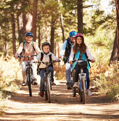 Grandparents and kids cycling on forest trail, California